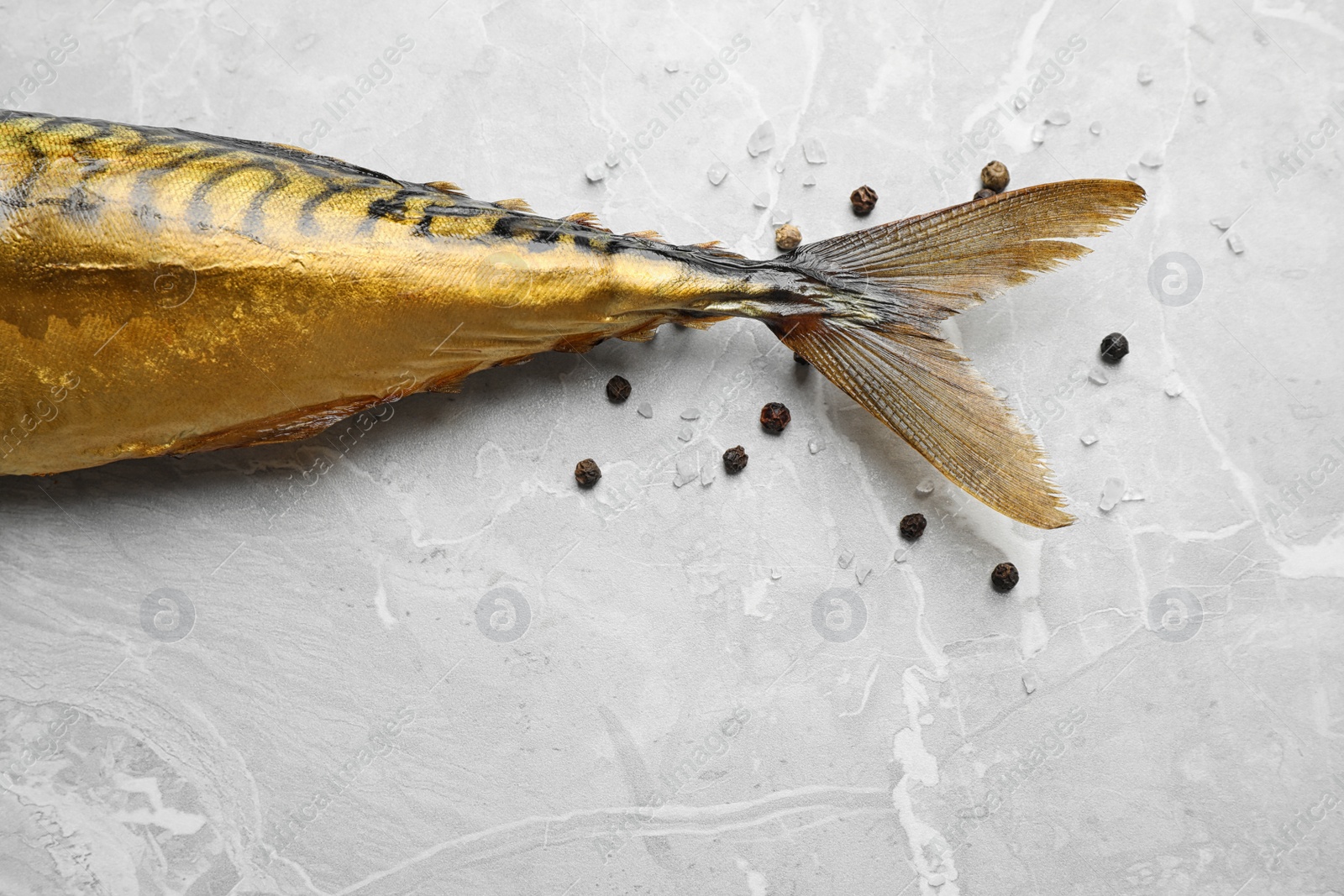 Photo of Tasty smoked fish on light grey marble table, closeup. Space for text