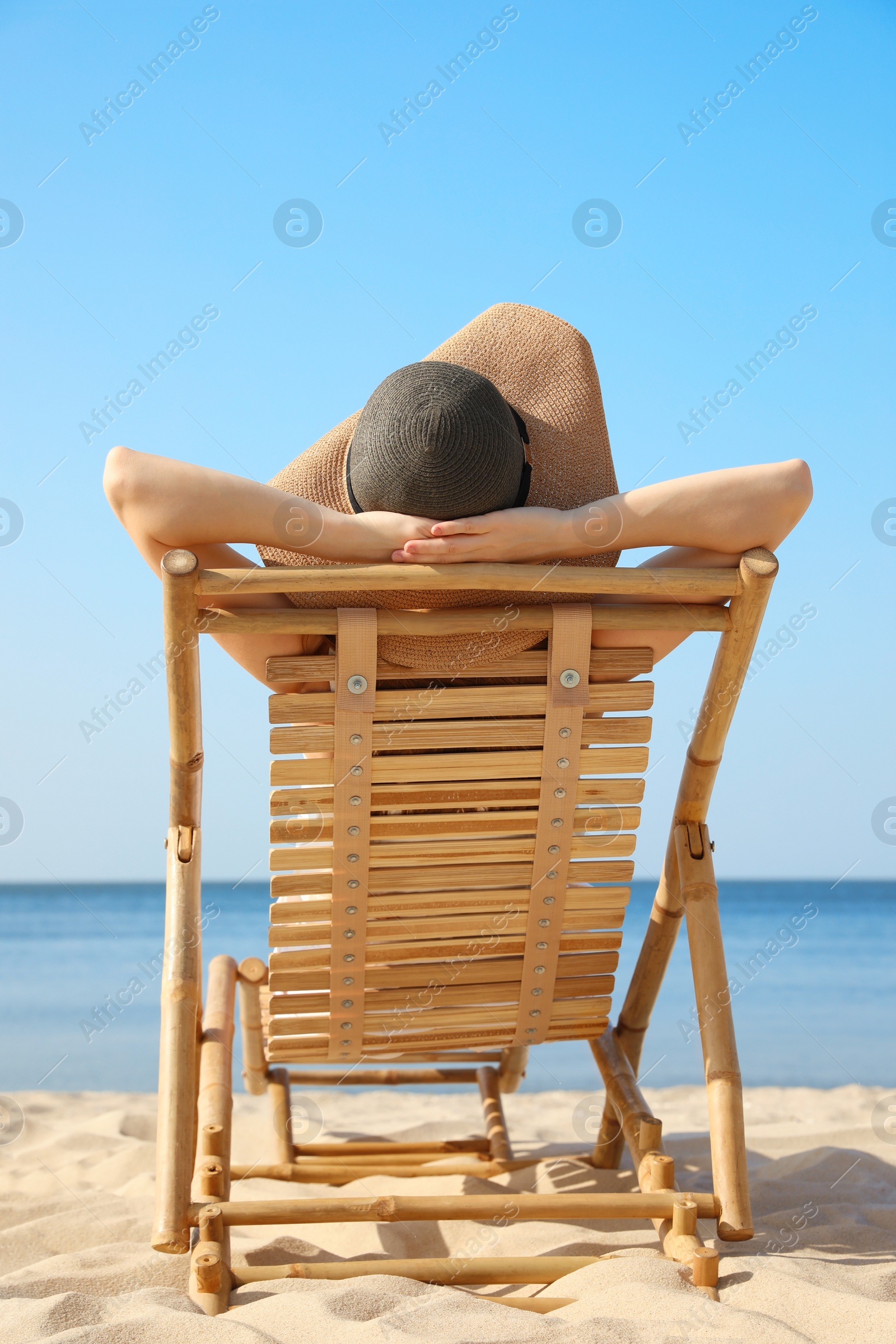 Photo of Young woman relaxing in deck chair on sandy beach