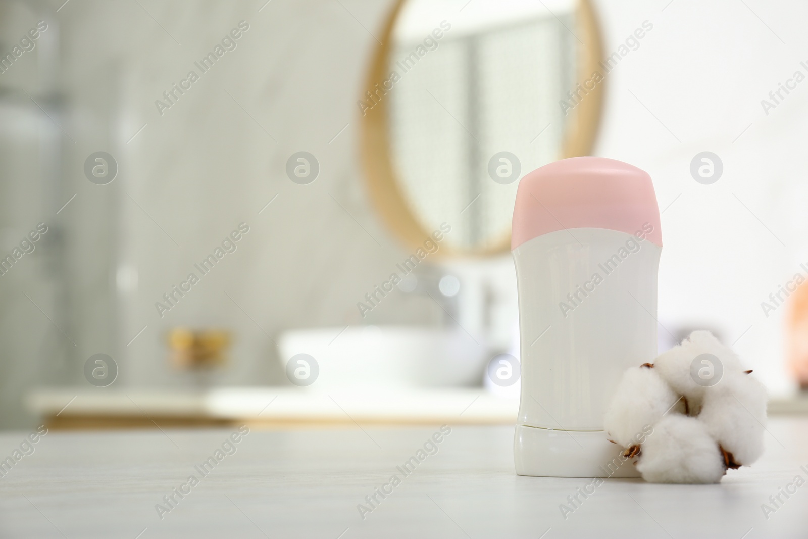 Photo of Deodorant with cotton flower on table in bathroom. Space for text