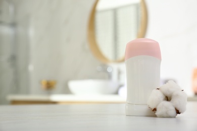 Photo of Deodorant with cotton flower on table in bathroom. Space for text