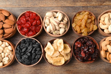 Photo of Composition of different dried fruits and nuts on wooden background, top view