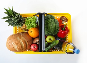 Photo of Shopping basket with grocery products on white background, top view