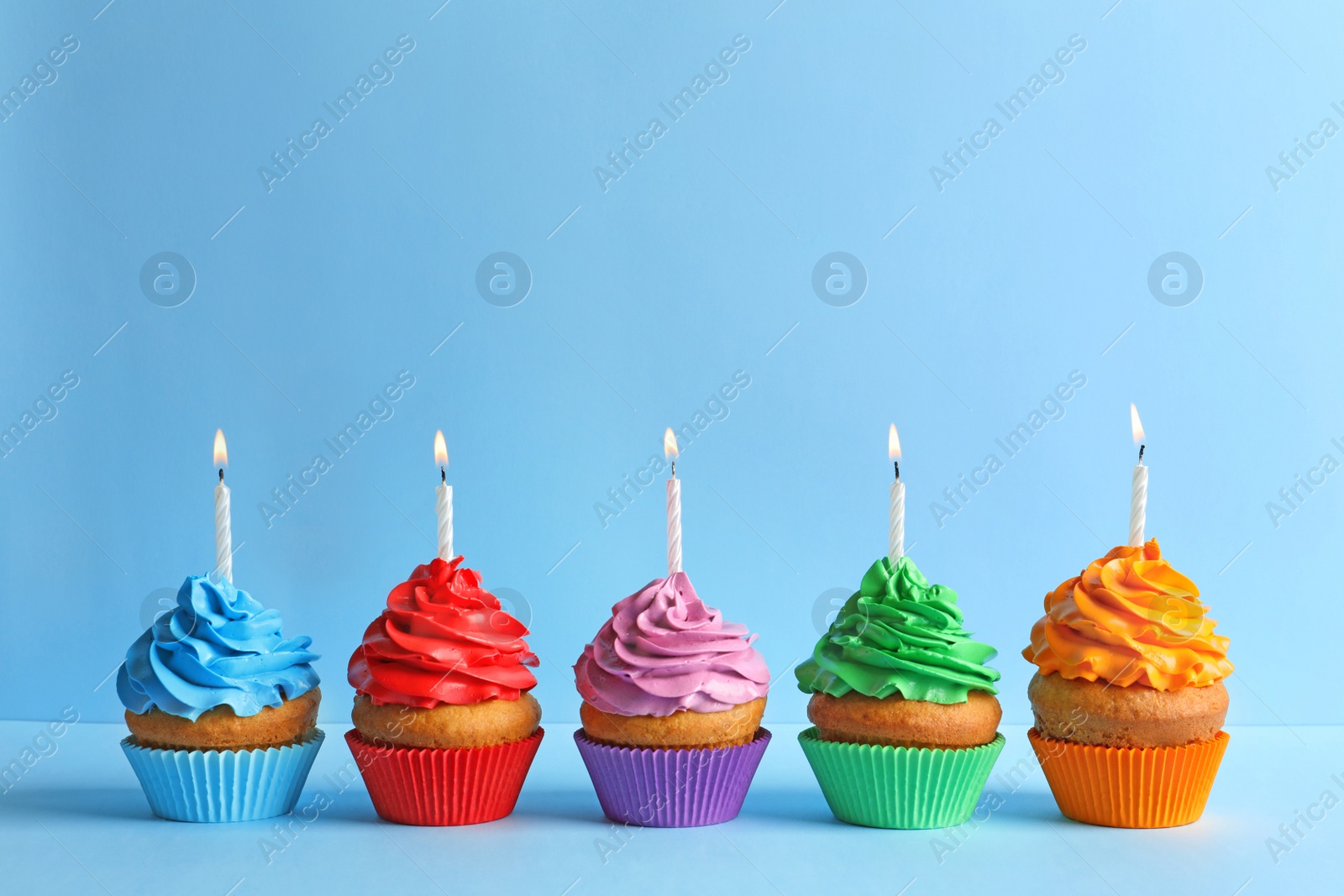 Photo of Delicious birthday cupcakes with candles on color background