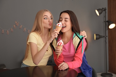 Photo of Young women fooling around with ice cream indoors. Happy laughter