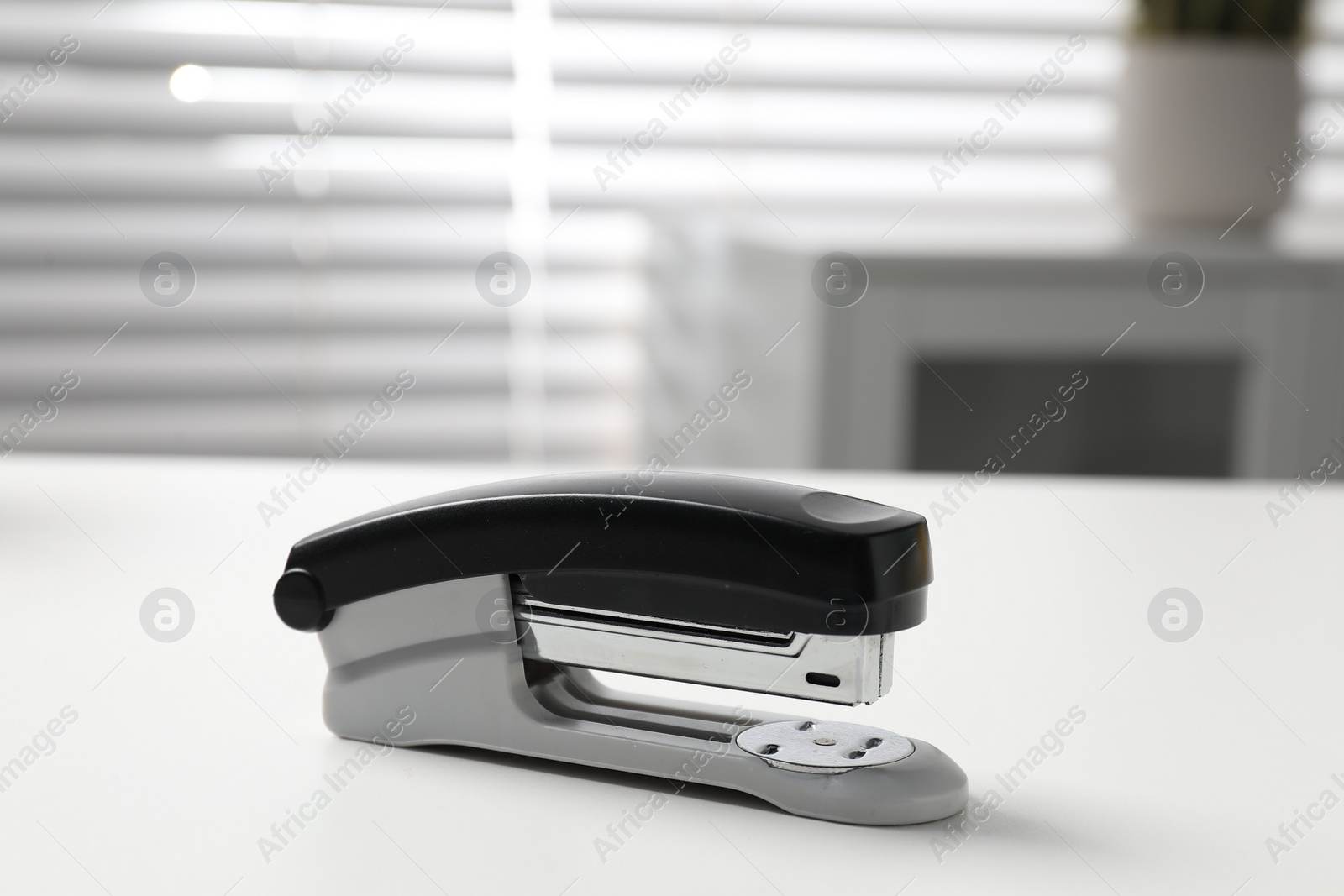 Photo of One stapler on white table indoors, closeup