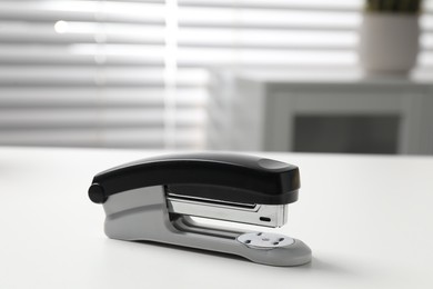 Photo of One stapler on white table indoors, closeup