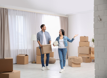 Photo of Happy couple in room with cardboard boxes on moving day