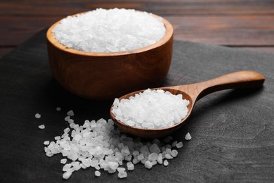Photo of Spoon and bowl of natural sea salt on wooden table