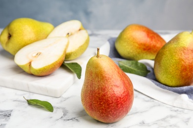 Photo of Ripe juicy pears on marble table against blue background