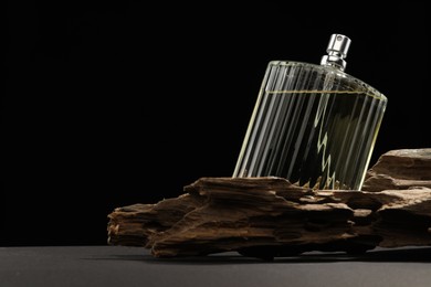 Photo of Luxury men`s perfume in bottle on grey table against black background, space for text