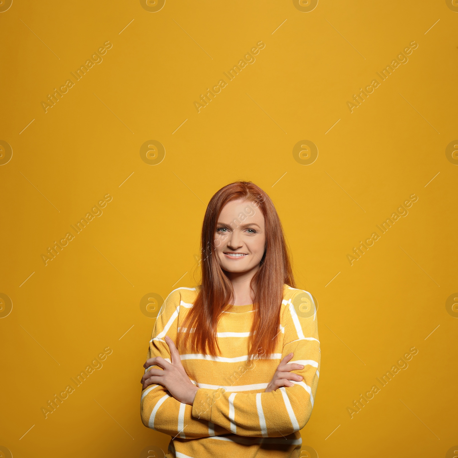 Photo of Candid portrait of happy young woman with charming smile and gorgeous red hair on yellow background