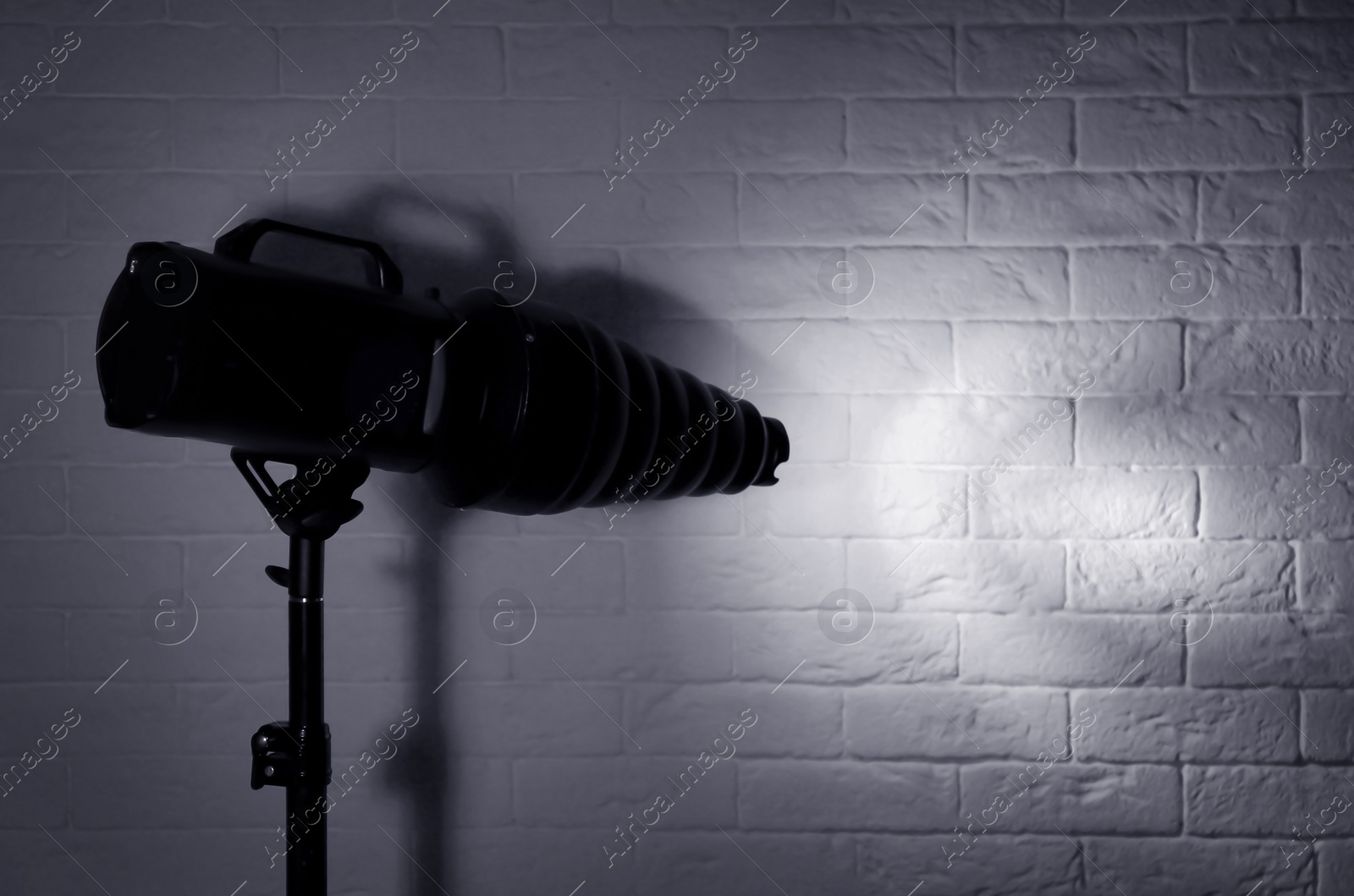 Photo of Professional photo studio lighting equipment near brick wall. Space for text