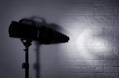 Photo of Professional photo studio lighting equipment near brick wall. Space for text