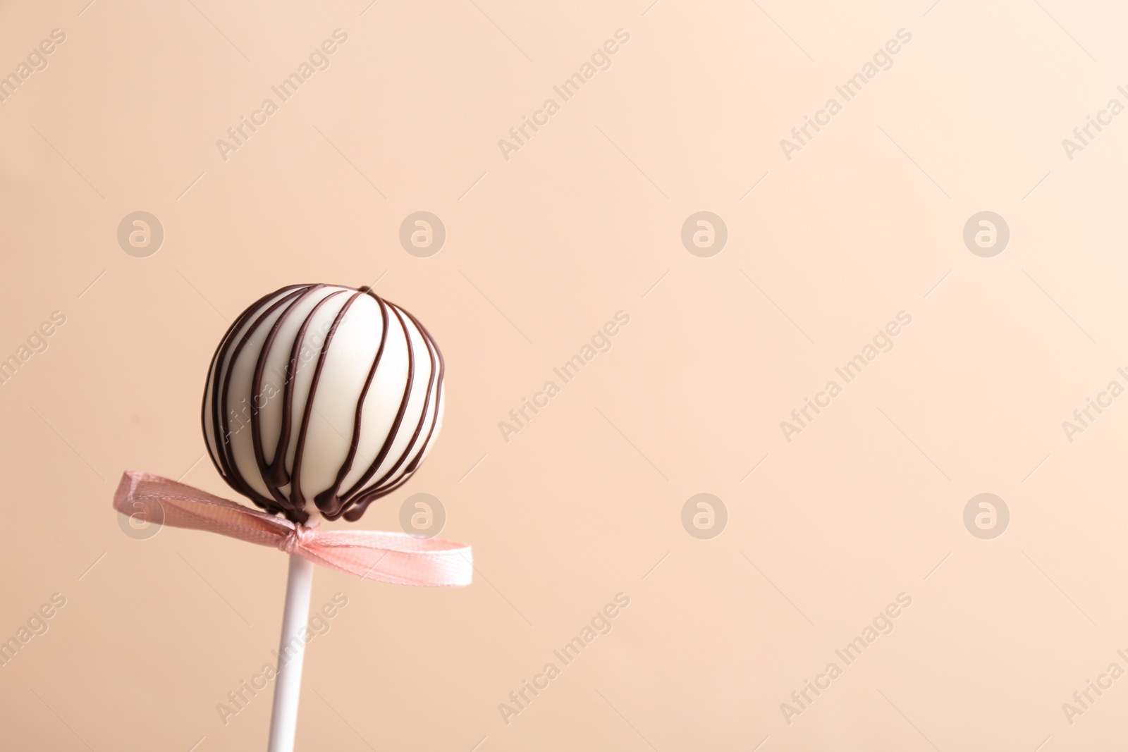 Photo of Tasty cake pop with bow on beige background. Space for text