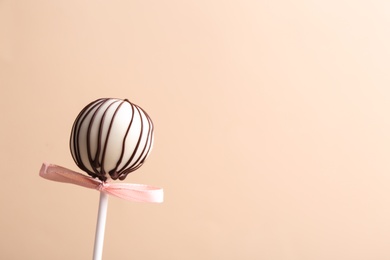 Tasty cake pop with bow on beige background. Space for text