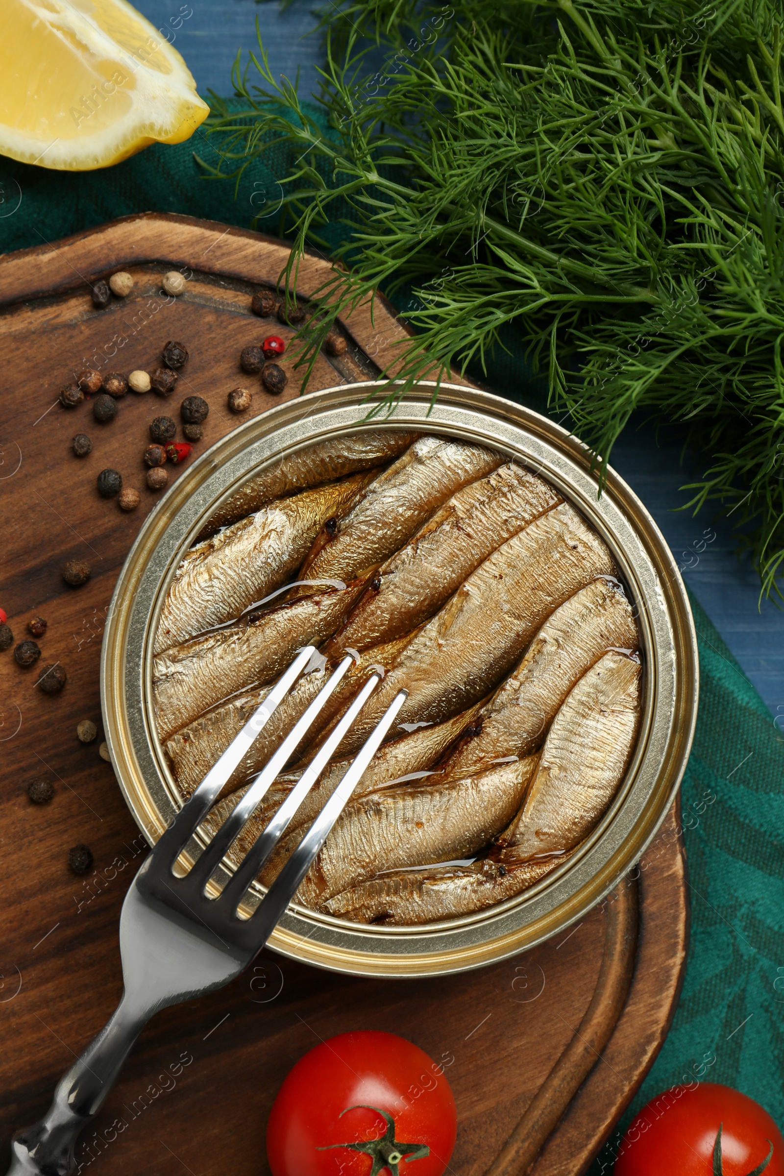 Photo of Tin can with tasty sprats served on table, flat lay