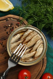 Tin can with tasty sprats served on table, flat lay