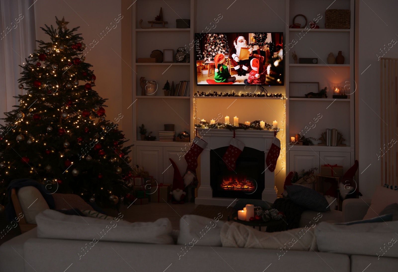 Photo of TV set with Christmas movie above fireplace in cosy room. Winter holidays atmosphere