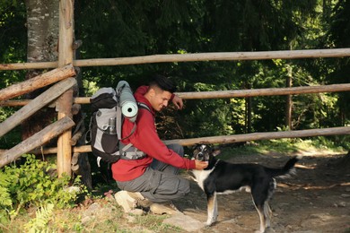 Photo of Tourist with backpack stroking cute dog outdoors