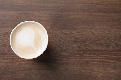 To-go drink. Tasty coffee in paper cup on wooden table, top view. Space for text