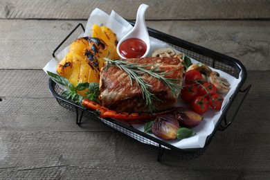 Photo of Delicious grilled meat and vegetables served with sauce on wooden table