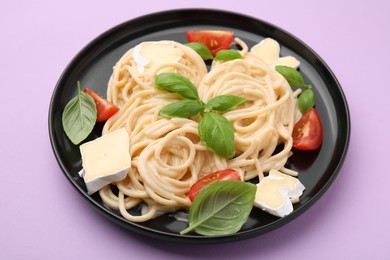 Photo of Delicious pasta with brie cheese, tomatoes and basil leaves on violet table, closeup