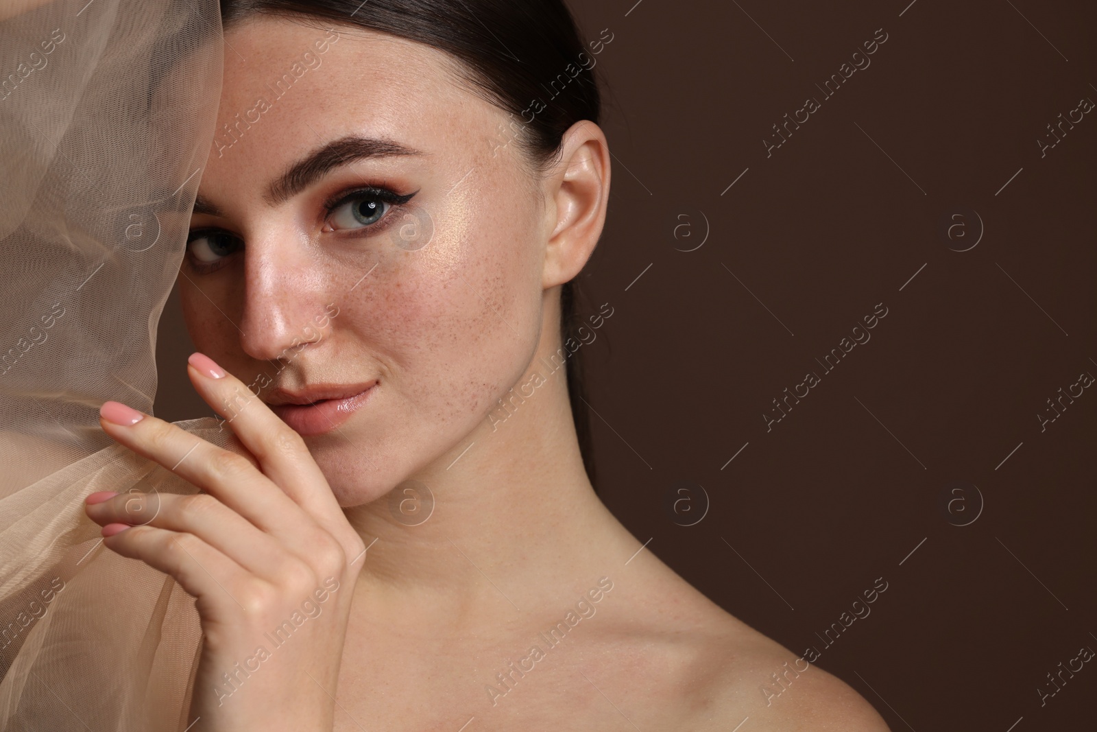 Photo of Fashionable portrait of beautiful woman with fake freckles on brown background, closeup. Space for text