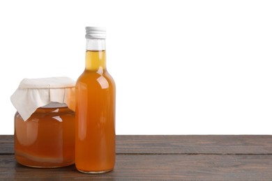 Delicious kombucha in glass bottle and jar on wooden table against white background, space for text