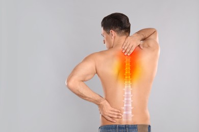 Man suffering from pain in back on light grey background