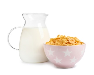 Bowl with crispy cornflakes and jug of milk on white background