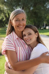 Family portrait of mother and daughter hugging outdoors