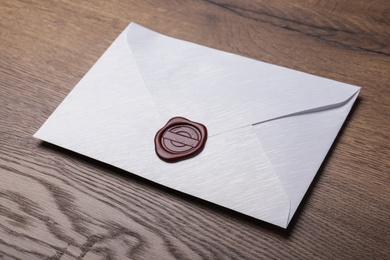 Photo of White envelope with wax seal on wooden table