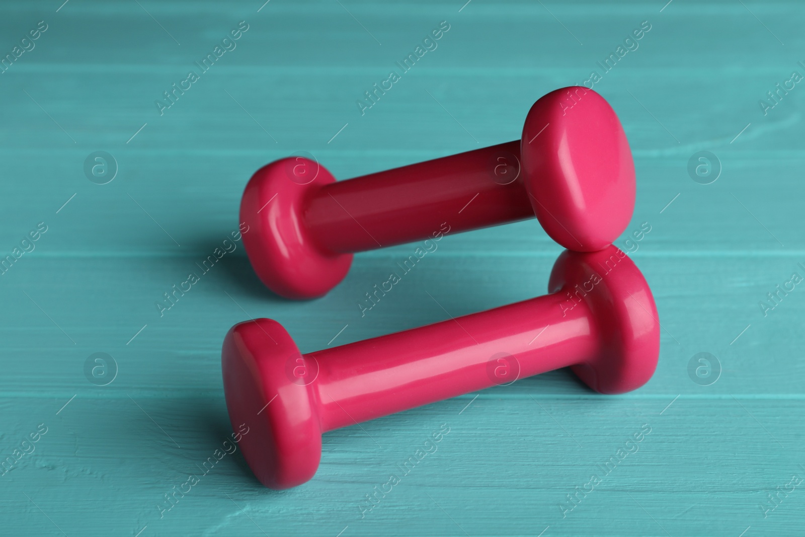 Photo of Pink vinyl dumbbells on turquoise wooden table