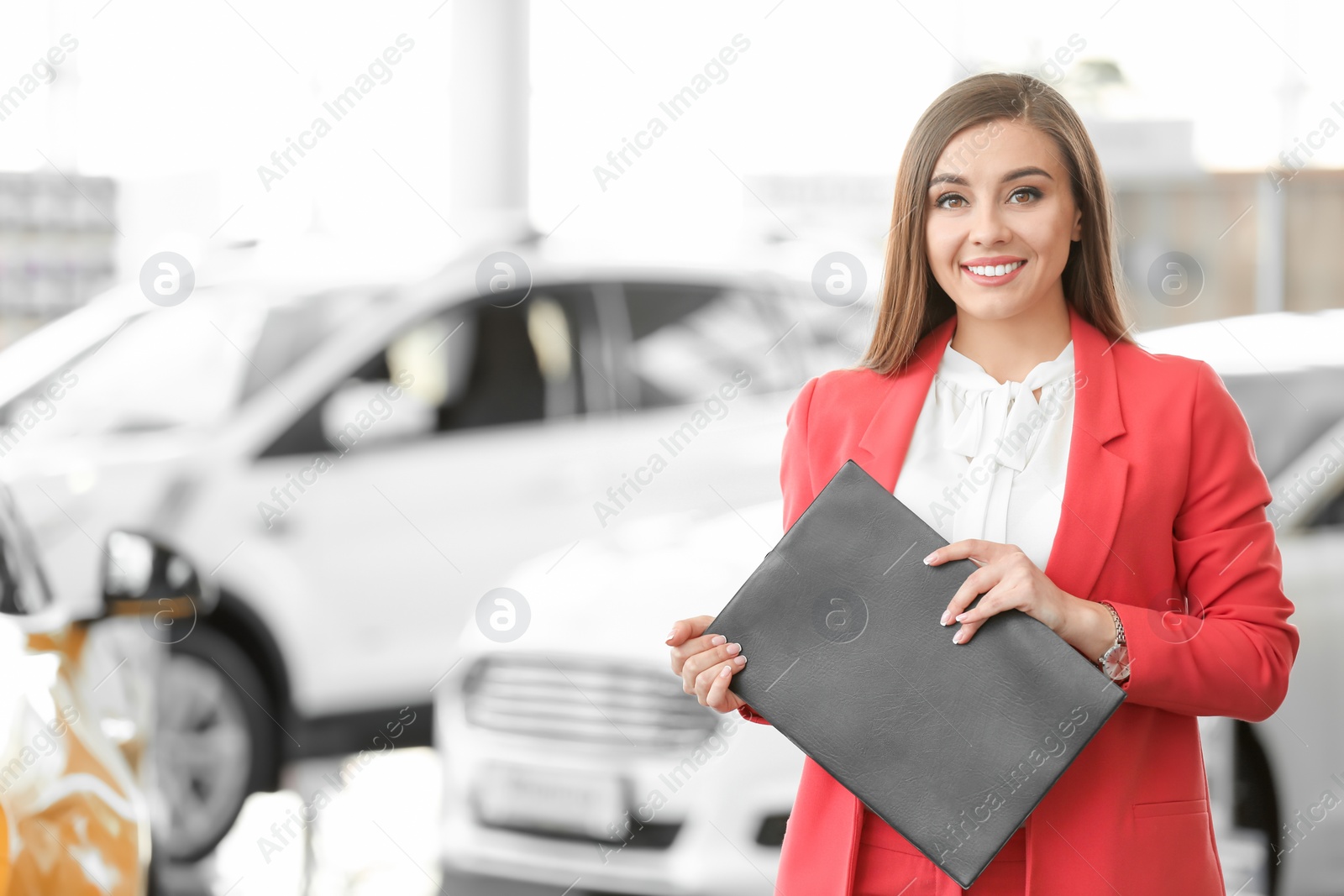 Photo of Young woman with clipboard in car salon