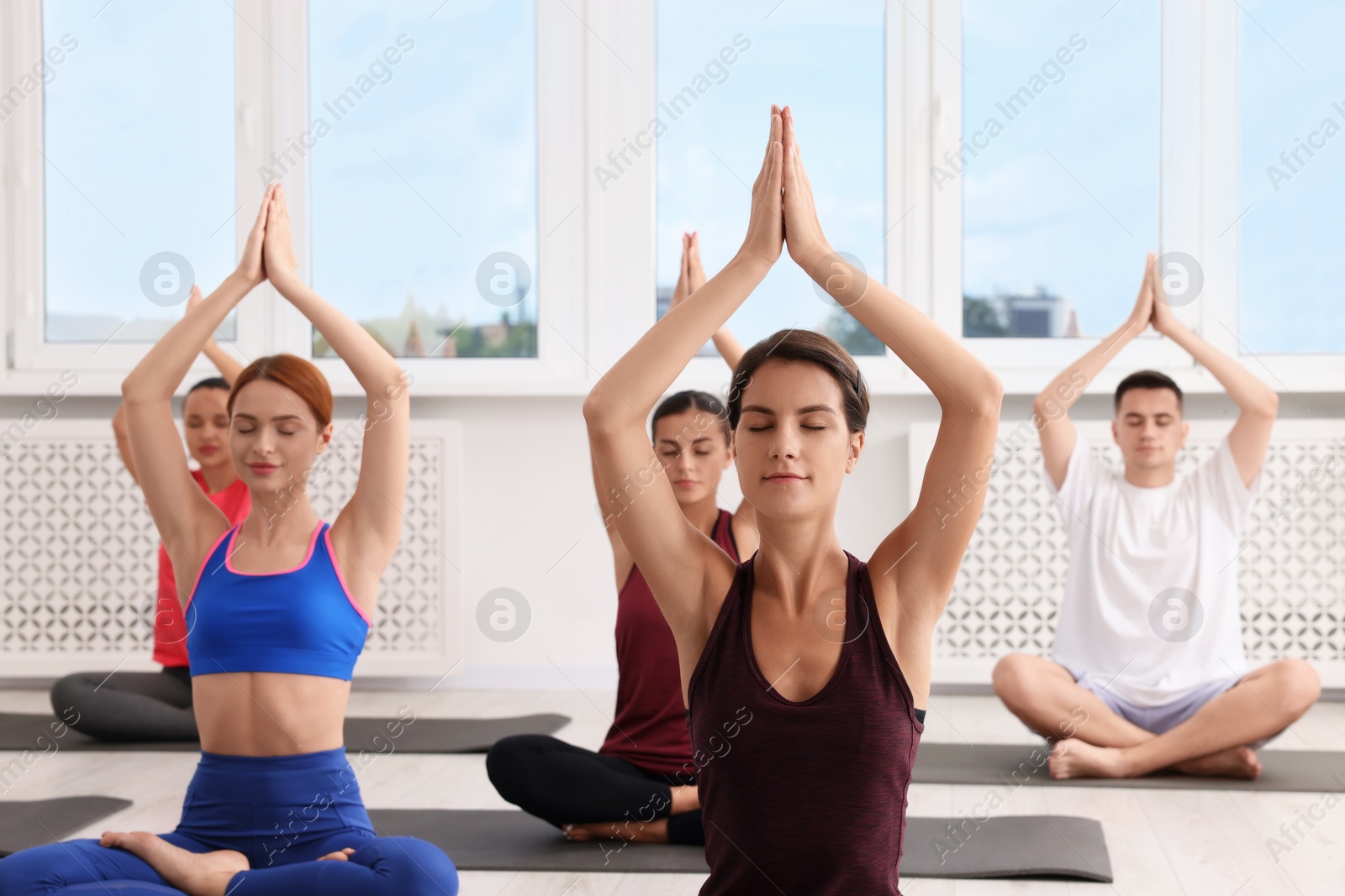 Photo of Group of people practicing yoga on mats indoors