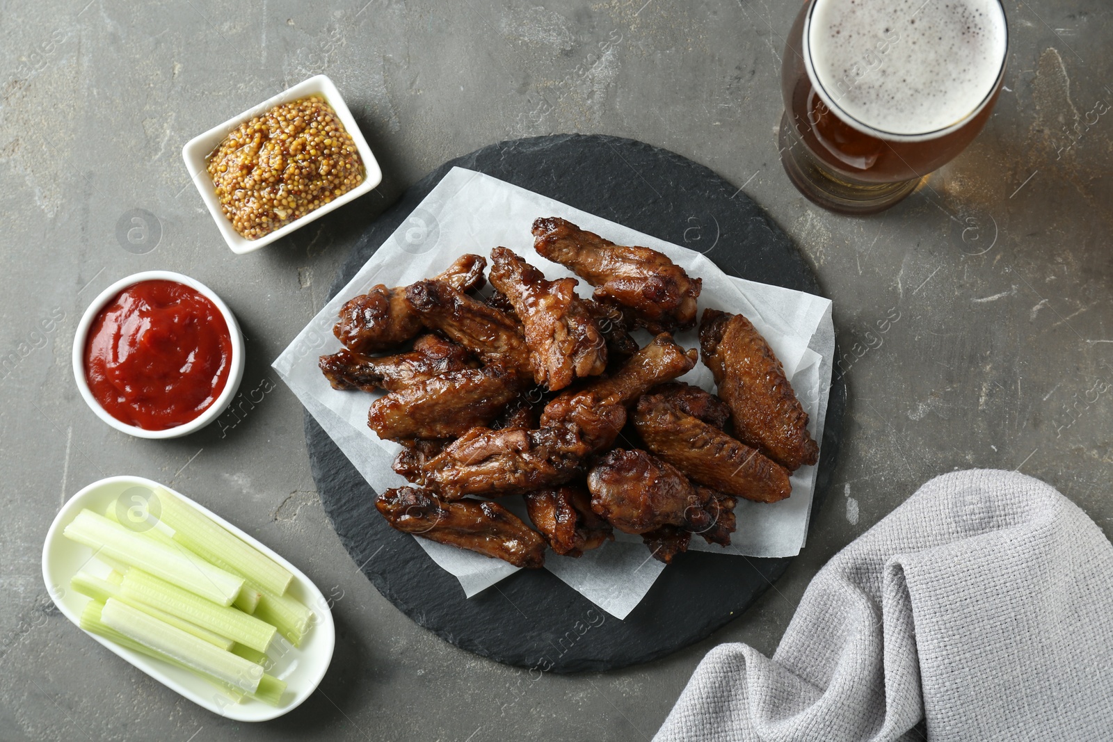 Photo of Delicious chicken wings served with beer on grey table, flat lay