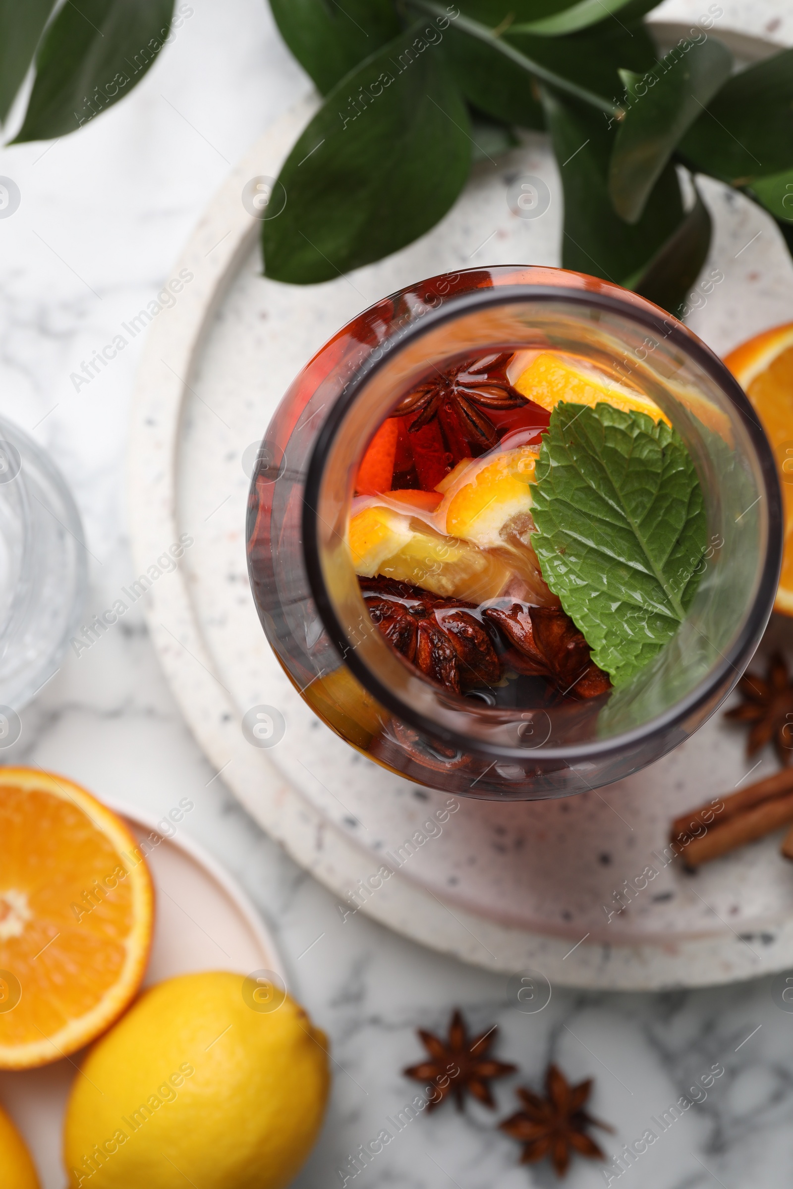 Photo of Delicious punch drink, spices and citrus fruits on white marble table, flat lay