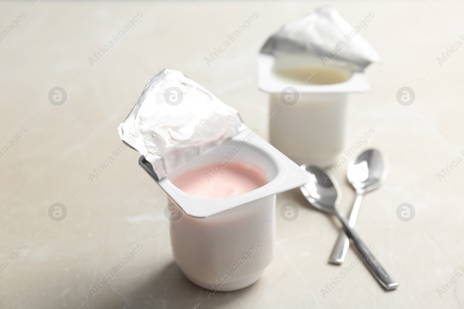 Photo of Plastic cups with different yogurts on light background