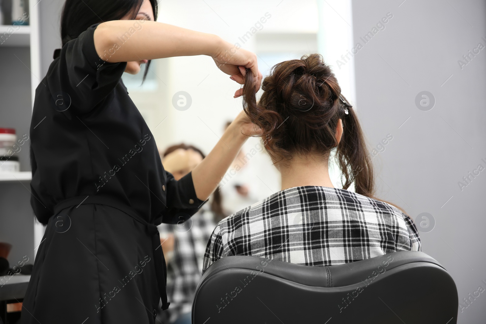 Photo of Professional female hairdresser working with client in salon