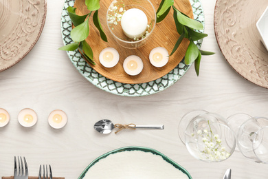 Elegant table setting with green plants on white wooden background, flat lay