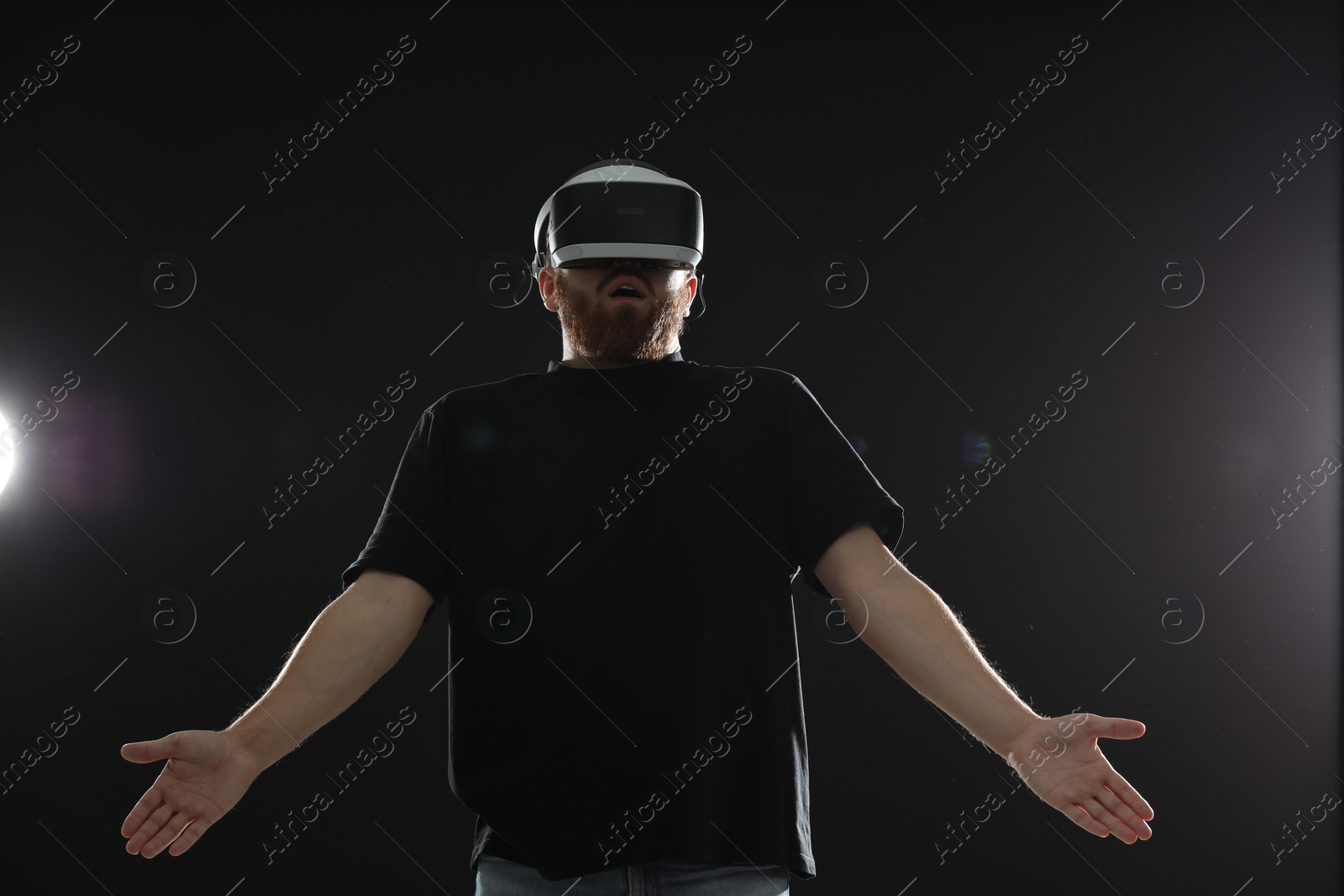 Photo of Surprised man using virtual reality headset on black background