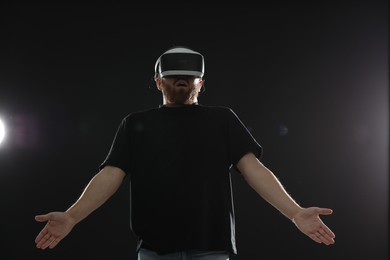 Photo of Surprised man using virtual reality headset on black background