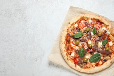 Photo of Tasty pizza with anchovies, basil and olives on white table, top view. Space for text