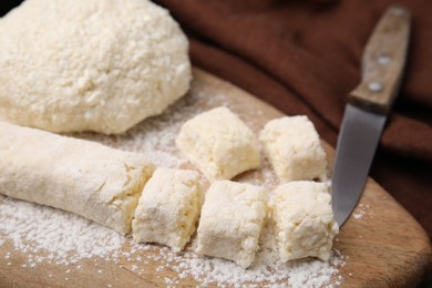 Photo of Making lazy dumplings. Raw dough, flour and knife on wooden board, closeup