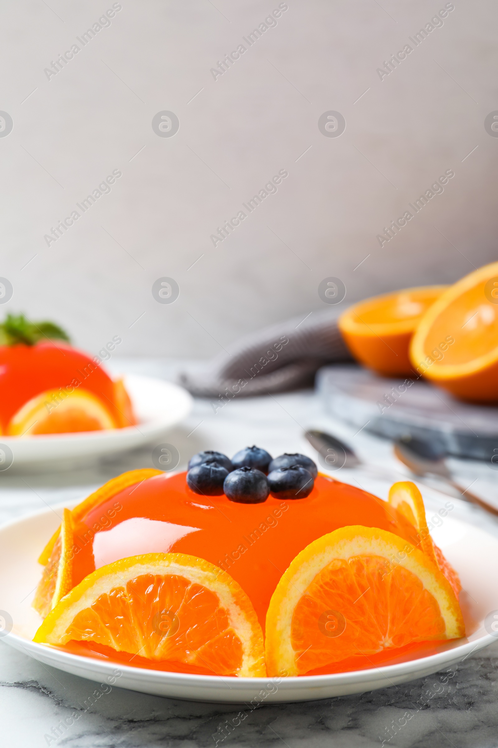 Photo of Delicious fresh jelly with orange slices and blueberries on marble table, space for text