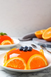 Photo of Delicious fresh jelly with orange slices and blueberries on marble table, space for text