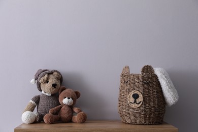 Photo of Child's toys and wicker basket on chest of drawers near light grey wall indoors