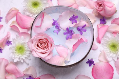 Flat lay composition with bowl of water and beautiful flowers on light table. Spa treatment