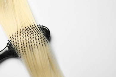 Photo of Stylish brush with blonde hair strand on white background, top view