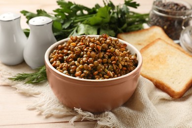 Photo of Delicious lentils in bowl served on table, closeup